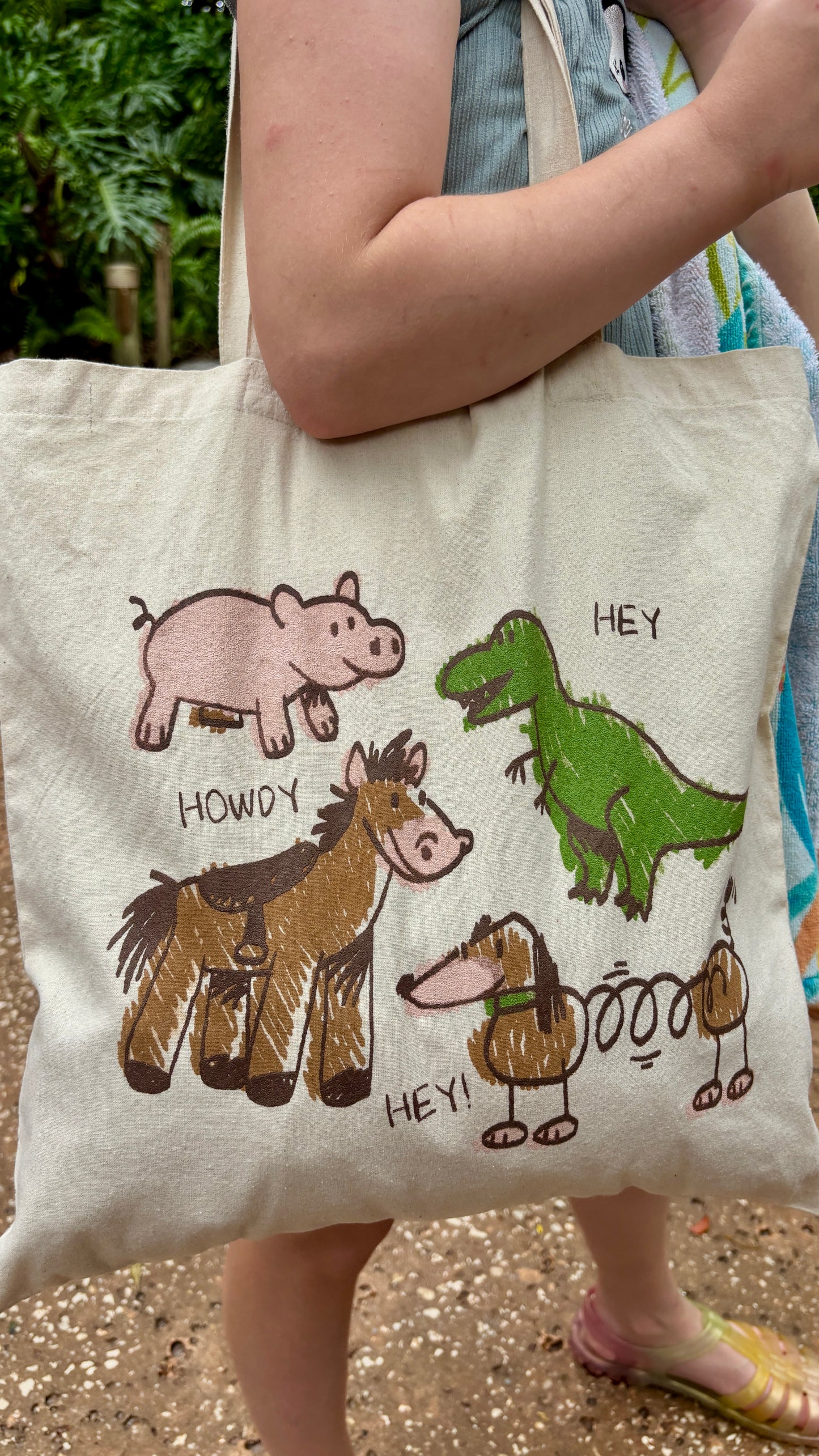 Toy Story inspired tote bag with crayon-style drawings of Rex, Hamm, Bullseye, and Slinky Dog on off-white cotton canvas