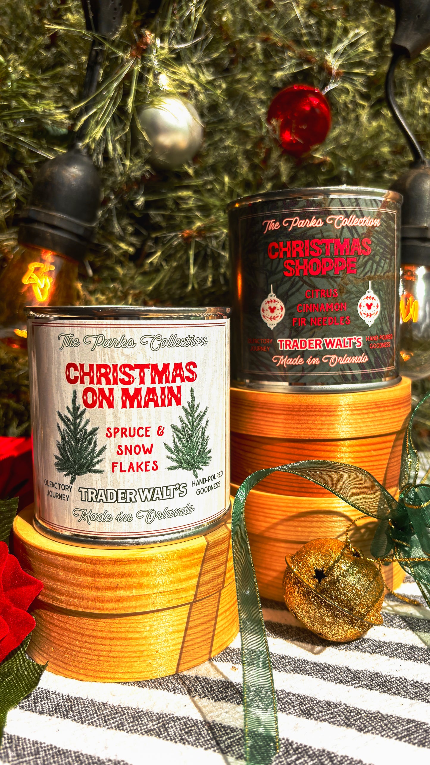 Disney-inspired Christmas on Main candle held in front of a decorated holiday tree. Trader Walt’s candle label features spruce branches and festive design, evoking Main Street Christmas and Mickey-style holiday magic.
