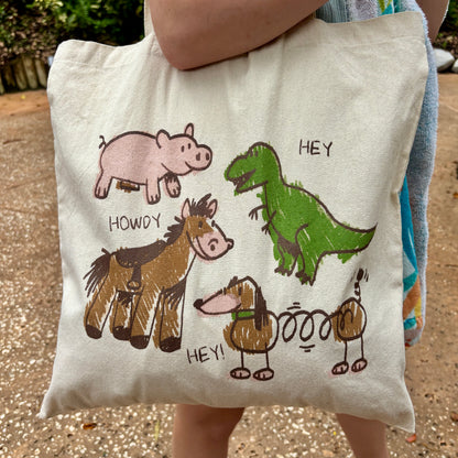 Toy Story inspired tote bag with crayon-style drawings of Rex, Hamm, Bullseye, and Slinky Dog on off-white cotton canvas