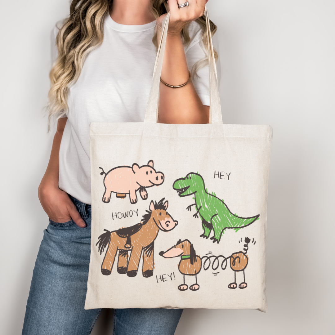 Toy Story inspired tote bag with crayon-style drawings of Rex, Hamm, Bullseye, and Slinky Dog on off-white cotton canvas